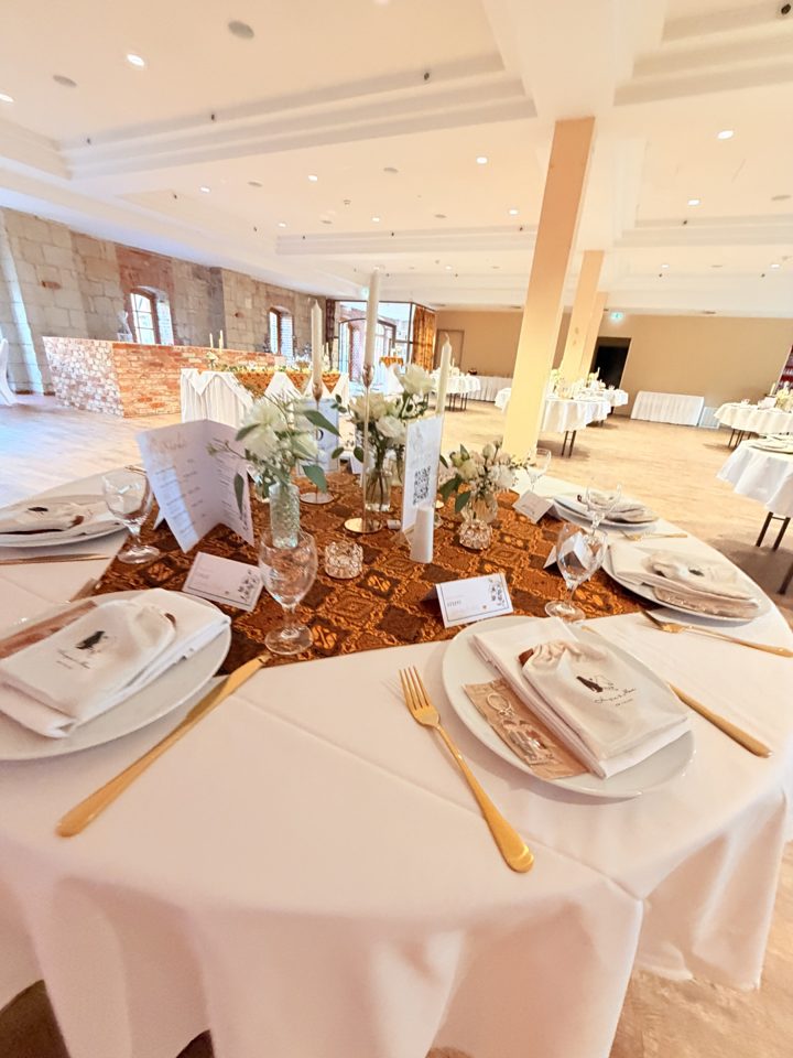 Festlich eingedeckter Tisch mit goldenem Besteck im Saal der Schlossmühle Quedlinburg
