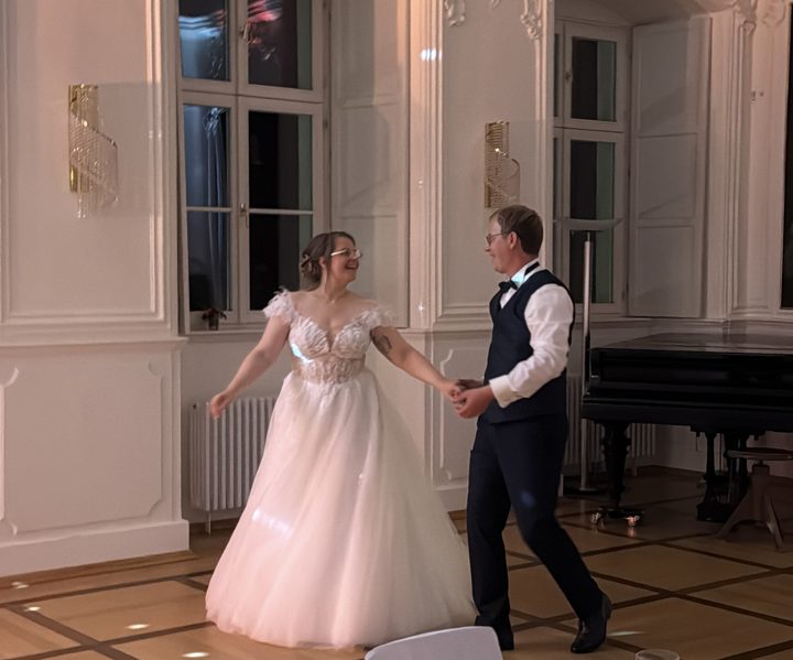 Brautpaar beim Eröffnungstanz in einem hellen Saal mit Flügel