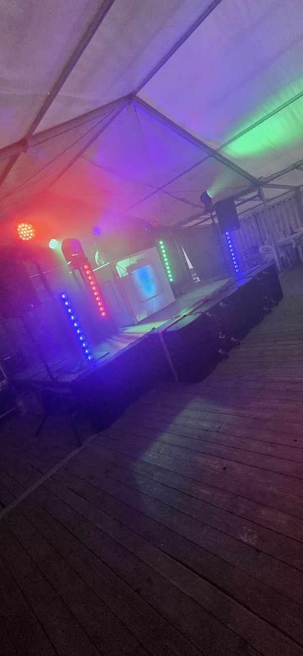 Festzelt mit buntem Licht, Lichtsäulen und DJ-Pult auf der Bühne