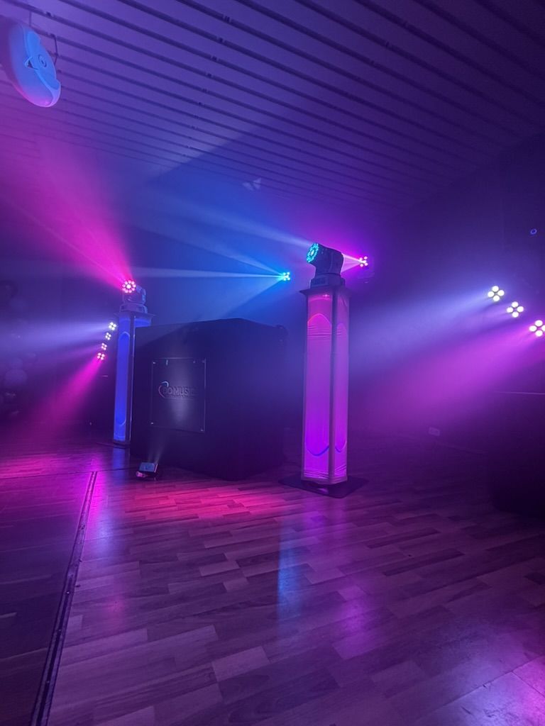DJ-Pult zwischen zwei Lichtsäulen mit Moving Heads und Nebel