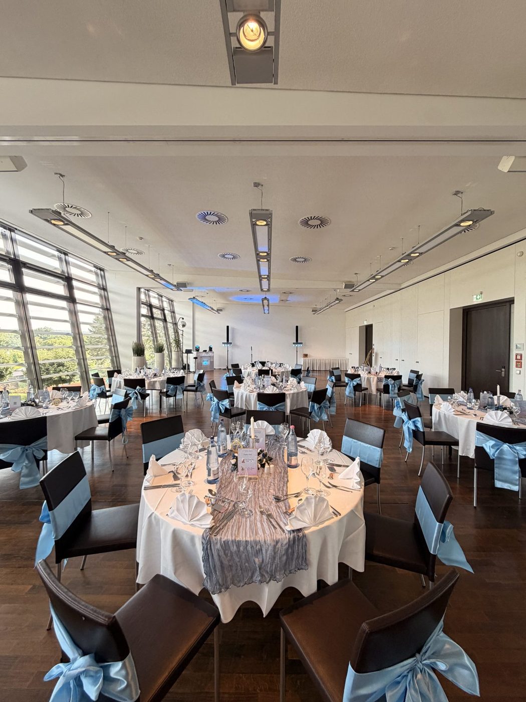 Saal im Hotel am See mit runden Tischen und hellblauen Stuhlschleifen