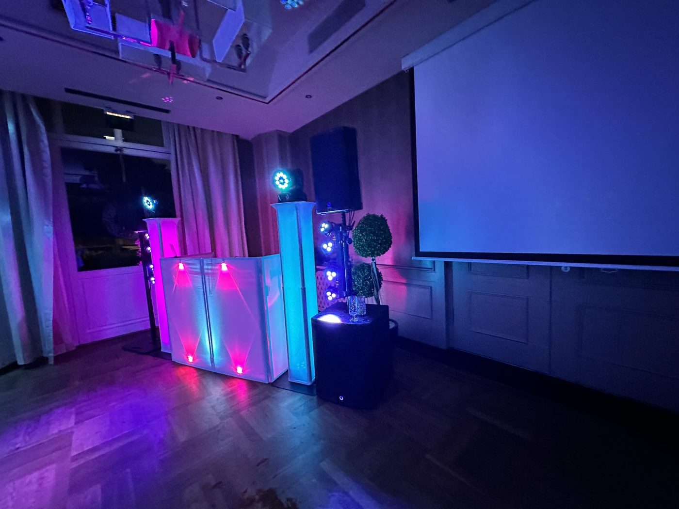 Saal im Hotel Schönau mit pinkem und blauem Licht vor einer Leinwand