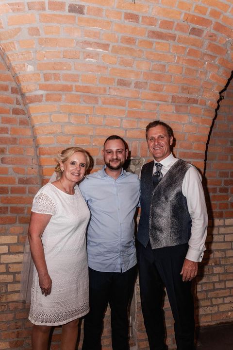 Hochzeitsfoto im Backsteingewölbe: Brautpaar und DJ Marco Hilse vor der Backsteinwand