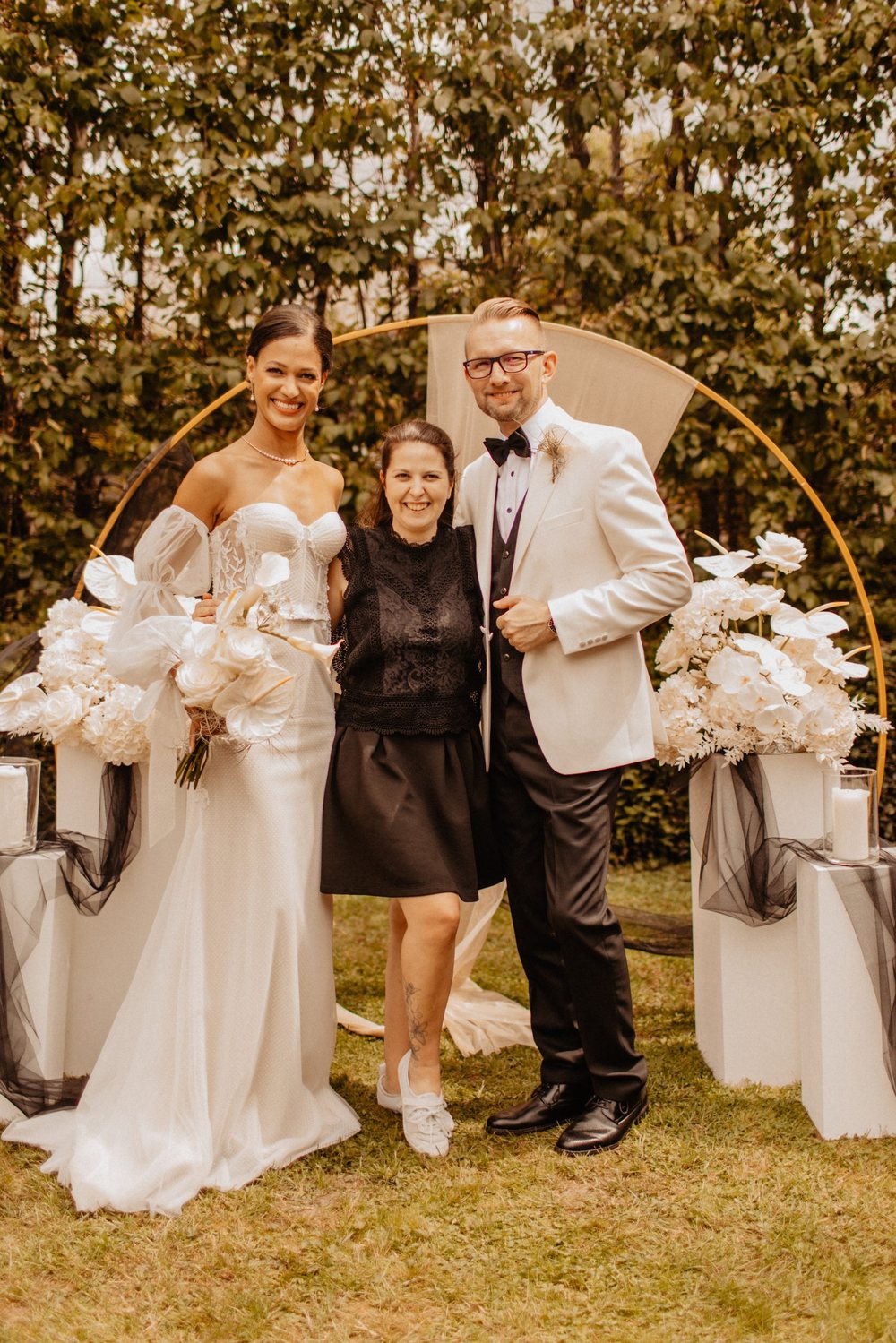 Hochzeitsplanerin mit einem Brautpaar vor dem Traubogen